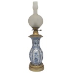 Antigo lampião montado com vaso balaústre em porcelana decorada em azul. Bojo ornado por reservas e faixas verticais com ramos floridos. Apresenta frisos horizontais recortados por estilizações florais. Montagem em bronze com queimador e regulador de chama, encimado por globo em vidro acetinado, rematado ao topo por adorno cilíndrico. Base circular larga, realçada por pequenos adornos geométricos. 87 x 20 cm.