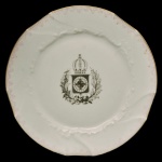 LIMOGES, France. Charles   - Prato em porcelana francesa apresentando centro com o Brasão de Armas Imperial Brasileiro. Serviço feito de encomenda do serviço imperial. Frequentemente utilizado no cerimonial de banquetes menos formais ou no serviço diário da família no Palácio de São Cristóvão (c. 1870-1889). O exemplar distingue-se pela aba com reserva em tonalidade rósea, ornamentos em precisos relevos "rocaille" e debrum em ouro com pátina do tempo, e do IHGB como encomenda direta do Imperador para uso em serviço diário.