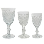 BACCARAT - Conjunto de 45 copos em cristal francês de pé alto. Bojos de formato cônico, lapidados e ornados por largas faixas em bico de jaca. Hastes retas, facetadas e abauladas ao centro, apoiadas em bases circulares lavradas com sulcos em leque, sendo  15 copos p/ água (17 cm). 15 copos p/ vinho tinto (16 cm) e 16 copos p/ vinho branco (15 cm).