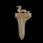 Rara e antiga ponta de lança chinesa em jade, esculpida e ornamentada por volutas, taches e estilizações, ladeada por figura de dragão. Possíveis infiltrações calcificadas. Possivelmente servindo de modelo de demonstração para confecção de armas em bronze. 12 x 6 cm.