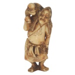 Netsuke em chifre de cervo representando um adestrador de macaco, 6 x 3 cm.