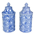 Par de potes decorativos em cerâmica artesanal com ornamentação clássica em azul sobre branco, com padronagens florais e galhos intrincados em toda a sua extensão. Corpo cilíndrico com tampa removível e pega na forma de pinha. Manufatura nacional Luiz Salvador, Itaipava. 26 x 12 cm.