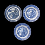 Conjunto de 19 pratos circulares em louça inglesa no padrão Blue Willow. Apresenta decoração em esmalte de tom azul cobalto sobre fundo branco no padrão conhecido como Pombinhos. Marcas das manufaturas no verso. Constando de 14 pratos rasos (23) e 5 pratos fundos (23).