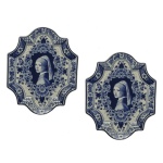 Par de placas em cerâmica em azul de Delft (Delfts Blauw), uma famosa tradição de cerâmica holandesa desenvolvida na cidade de Delft. Reproduz no centro de cada placa a icônica obra de arte "Moça com o Brinco de Pérola" (Meisje met de Parel), pintada pelo mestre holandês Johannes Vermeer por volta de 1665. Bordas recortadas e ornamentadas com padrões florais barrocos. 22 x 18 cm.