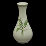 CHRISTIAN DIOR, Limoges. Milly-la-Forêt  Vaso em porcelana francesa da manufatura de Limoges com decoração floral de lírios do vale. O design apresenta a inscrição "Le Muguet fleur porte-bonheur" (O Lírio do Vale, Flor da Sorte) e está ligado ao nome da vila onde Monsieur Dior desenhava suas coleções. 21 x 11 cm.