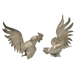 Par esculturas em prata de lei provavelmente brasileira, repuxada e cinzelada, representando galos de briga, ricamente ornamentados com finos detalhes na plumagem e nos movimentos. Apresenta contrastes. 16 x 18 x 11 cm e 18 x 13 x 16 cm. Peso 461 gramas e 458 gramas.