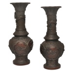 Séc. XIX - Par de vasos orientais provavelmente japoneses, em bronze patinado, de formato balaústre alongado, ornamentados em relevo por pássaros e flores em reservas no formato de leques. Bojos ovalados, encimados por longos gargalos em corneta, realçados com animais e plantas sobre fundos estampados com gregas repetidas. Bordas reviradas e lisas. Bases circulares e salientes. 30 x 12 cm.