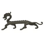 Escultura chinesa em bronze patinado, representando dragão caminhando, com a boca aberta e os dentes à mostra.14 x 32 x 4 cm.