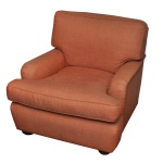 Poltrona clássica de estilo club chair com estofamento em tom terracota. Se destaca por seus braços arredondados e robustos, almofada de assento solta e espessa, além de pés curtos e discretos de madeira na base. O design foca no máximo conforto, trazendo uma estética aconchegante e atemporal que se encaixa muito bem em salas de estar tradicionais e bibliotecas. 85 x 85 x 85 cm.