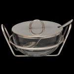 RIVA - Açucareiro em cristal com alças laterais e tampa protetora em metal prateado. Comumente utilizado para servir açúcar à mesa de forma elegante, contando com uma pequena abertura na tampa para acomodar a colher. 7 x 15 cm.