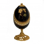 Caixa de música em formato de ovo. Apresenta um  acabamento em esmalte azul-noite (Bleu nuit) e decorada com flores douradas. O ovo é montado em bronze dourado (ormolu) e adornado com pequenas pedrarias ou cristais