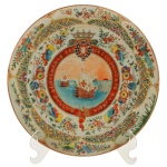 Prato em porcelana chinesa, Companhia das Índias, pertencente ao serviço Comemorativo do Quarto Centenário do Descobrimento da Índia. Pertenceu a Francisco Basto, Luiz Resende. Comprado em 10/07/1950. 25 cm. Retrata caravelas portuguesas no centro, emolduradas por um brasão com coroa e a inscrição "Quarto Centenário do Descobrimento da Índia". Borda decorada com esmaltes policromados, apresentando motivos fitomorfos, geométricos e pequenas reservas com insetos.