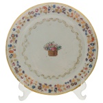Prato em porcelana chinesa, Companhia das Índias, pertencente do Serviço Coelho e Castro. Apresenta fundo branco ornamentado ao centro com reserva exibindo um cesto de flores em policromia. Aba e bordas circulares decoradas por guirlandas floridas, arabescos e esmaltes coloridos. Peça idêntica reproduzido na pág. 116 do livro Louça da Aristocracia no Brasil. 24 cm.