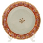 RERVIÇO DAS ROSAS DE D. JOÃO V  Raríssimo prato em porcelana chinesa, Companhia das Índias, pertencente ao Serviço das Rosas de D. João VI. Este icônico serviço de jantar foi utilizado pelo monarca português Rei Dom João VI em sua residência na Fazenda Real de Santa Cruz, no Rio de Janeiro. Acredita-se que o aparelho tenha sido trazido pela família real portuguesa em sua transferência para o Brasil em 1808. Borda apresentando uma tonalidade característica em laranja (rouge de fer) decorada com uma aplicação de rosas com esmalte rosa entremeadas por folhagens e detalhes em ouro. Centro da peça com um arranjo floral dourado. 25 cm.