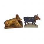 COWPARADE  Lote constando 2 figuras colecionáveis em miniatura da exposição CowParade, sendo:A) Modelo Egyptian Princess na cor dourada produzido pela Westland Giftware e está atualmente aposentado, tornando-o um achado raro para colecionadores.B) Modelo Tutancowmon (Item 9126), feita de resina com pintura azul, dourada e detalhes em mosaico. 10 x 15 x 6 cm.