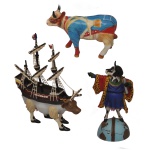 COWPARADE  Lote constando 3 figuras colecionáveis em miniatura da exposição CowParade, sendo:A) Figura colecionável de cerâmica modelo "Revolutionary War Cow" de 2004, produzida pela Westland Giftware. 12 x 16 x 6 cm.B) Figura de resina em miniatura "Mooflower", inspirada no navio de mesmo nome e parte de uma famosa exposição de arte pública. Criada por Westland Giftware, esta peça específica foi apresentada na instalação de Boston. O design combina uma vaca com corpo de navio, completo com mastros, velas e bandeiras, além de pernas vestidas com sapatos pretos. 22 x 17 x 5 cm.C) Figura colecionável de resina "Cowlumbus" de 2006, retratando uma vaca vestida como Cristóvão Colombo em cima de um globo da Westland Giftware. A peça é pintada à mão e mostra a vaca com uma capa de estampa de leopardo e segurando um pergaminho.