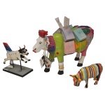 COWPARADE  Lote constando 3 figuras colecionáveis em miniatura da exposição CowParade, sendo:A) Figura colecionável modelo "Striped" criado pelo artista Cary Smith para o evento de Nova York em 2000. 9 x 16 x 5 cm.B) Figura colecionável da vaca modelo "Platinum Moodallion" de 2004, feita pela Westland Giftware para a Delta Airlines. 15 x 17 x 8 cm.C) Figura colecionável de vaca modelo "Ms. Moolevard on the Boulevard". O design original foi criado por Amber Felts para o evento de Houston em 2001. Feita de resina polida (polyresin) e é conhecida por sua decoração vibrante com joias falsas, lantejoulas e sacolas de compras em miniatura. 24 x 37 x 14 cm.