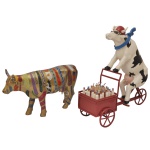 COWPARADE  Lote constando 2 figuras colecionáveis em miniatura da exposição CowParade, sendo:A) Figura colecionável modelo "Ta-krava-ta" criada pelos artistas Daniel Bidelnica e Peter Dvorsky para o evento de Bratislava em 2005. A peça apresenta um acabamento dourado decorado com uma pintura policromada de várias gravatas. A estatueta é feita de material sintético (resina). 19 x 30 x 9 cm.B) Figura colecionável modelo Lait Triporteur desenhado pela artista Martine Diotalevi para o evento de Paris em 2006. 34 x 32 x 11 cm.