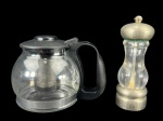 VIDROS, lote com duas (2) peças, sendo: A) 1 jarra para chá confeccionado em vidro com guarnições em plástico rígido na tonalidade preta, medindo 14x18x9,5cm e B) 1 pimenteiro confeccionado em acrílico translucido com guarnições em metal prateado com sinais de oxidação, medindo 17,5cm de altura.
