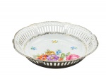 Schwarzenhammer, uma (1) fruteira confeccionada em porcelana alemã na tonalidade branca, galeria em vazados, decorado por flores e folhagens em policromia e guirlanda com realces em ouro, apresenta fio de cabelo na borda, medindo 5,5x22,5cm.