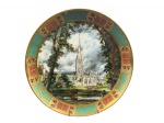 PORCELANA, um (1) prato decorativo confeccionado em porcelana na tonalidade branca, pintura de uma reprodução da famosa pintura "Salisbury Cathedral from the Bishop's Grounds" do artista John Constable em policromia, espessa faixa em ouro decorado por elementos vegetalistas e florais em policromia, medindo 30cm de diâmetro.