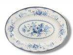 ÁGATA, uma (1) grande travessa oval confeccionada em ágata esmaltada na tonalidade branca da marca MÃE ÁGATA, decorado por flores e folhagens em monocromia na tonalidade azul com borda capeada em metal prateado, apresentando leves batidas e pequena mossa na borda, medindo 51x37cm.