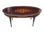 MOBILIÁRIO, uma (1) mesa de centro oval, confeccionada em madeira escura, tampo com decoração floral em marchetaria e galeria em vazados, pés torneados com apliques de adornos em bronze, apresentando ínfimas falhas no pé e pequenas manchas no tampo, medindo 46x103x49,5cm.