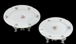 MZ Moritz Zdekauer (Produzida após 1918, ano da independência da Checoslováquia), duas (2) travessas ovais confeccionadas em porcelana theca na tonalidade branca, decorada por flores e folhagens em policromia, realces vegetalistas em relevo na pasta e filete em ouro na borda, apresenta falhas na douração, medindo 33,5x22cm e menor 27,5x18,5cm.