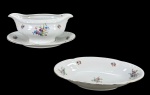 MZ Moritz Zdekauer (Produzida após 1918, ano da independência da Checoslováquia), lote com duas (2) peças, sendo: A) 1 molheira fixada ao presentoir, medindo 9,5x21x14cm e B) 1 covilhete, medindo 24x13cm, confeccionadas em porcelana theca na tonalidade branca, decorada por flores e folhagens em policromia, realces vegetalistas em relevo na pasta e filete em ouro na borda, apresenta falhas na douração.