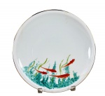 PORCELANA MAUÁ, um (1) prato decorativo confeccionado em porcelana na tonalidade branca, decorada por peixes e folhagens em policromia com borda filetada em ouro com falhas na douração, medindo 24,5cm.