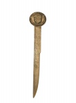 METAL DOURADO, um (1) abridor de cartas em metal dourado, com haste em formato de régua e medalhão superior em relevo com perfil de John F. Kennedy, 35th President 19171963, medindo 19,5cm. Leves sinais de oxidação.