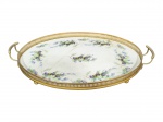 Max Dannheim, uma (1) bandeja oval confeccionada em faiança alemã na tonalidade branca, decorada por flores e folhagens em policromia com rachaduras, galeria em metal com pintura dourada, apresentando falhas, medindo 47x31cm.