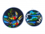 DIVERSOS, dois (2) pratos decorativos confeccionados em vidro pintado sendo: A) 1 com decoração de tucanos em policromia com asas de borboleta e moldura em alumínio, medindo 24cm de diâmetro e B) 1 com decoração de paisagem do Rio de Janeiro em policromia e asas de borboleta e moldura em alumínio, medindo 19cm.