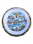 PORCELANA HLR BERLIN, um (1) prato decorativo confeccionado em porcelana na tonalidade branca, souvenir de Berlim, com composição policromada representando diversos monumentos e pontos turísticos da cidade, entre eles o Portão de Brandemburgo, Reichstag, Alexanderplatz e Catedral de Berlim. Apresenta brasão com o urso berlinense ao centro, borda recortada, elementos vegetalistas relevados com acabamento dourado, apresenta falhas na pintura, medindo 26,5cm.