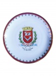 PORCELANA REAL, um (1) prato decorativo confeccionado em porcelana branca com brasão heráldico ao centro, encimado por coroa e ladeado por ramos vegetalistas, em decoração policromada, gravado em ouro PREFEITURA MUNICIPAL DE SÃO PAULO. Borda ornamentada em espessa faixa vinho com detalhes dourados, medindo 25,5cm.