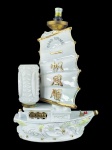 ABAJUR, um (1) abajur para duas (2) lâmpadas confeccionado em porcelana na tonalidade branca no formato de caravela, vela decorada com inscrição GOOD VOYAGE e caracteres orientais em relevo com adornos em douração, cúpula em vidro pintado na tonalidade branca, ausência da cúpula da parte superior, ferragens com sinais de oxidação, não testado e sem garantia de funcionamento, medindo 46cm de altura.