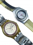 RELÓGIOS, dois (2) relógios de pulso da marca Swatch, sendo: A) um com caixa em metal prateado, mostrador branco com algarismos coloridos e pulseira em material sintético nas cores creme e preta, caixa com sinais de oxidação, não testados e sem garantia de funcionamento, caixa medindo 3,5x3,5cm, sinais de uso e B) um com caixa translúcida em tom amarelado, mostrador branco com calendário de dia da semana e data, mecanismo aparente no verso e pulseira metálica, caixa medindo 3,5cm, não testado e sem garantia de funcionamento.