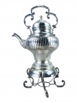 METAL PRATEADO, um (1) samovar confeccionado em metal espessurado a prata, corpo bojudo cinzelado em gomos torcidos, alça central fixa no feitio de arabescos, bico com elementos florais, base escalonada apoiada sobre 4 pés curvos com mossa, ausência do fogareiro, medindo 44,5x26cm.