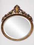 ESPELHO, um (1) espelho de parede oval bisotado, moldura em madeira com patina dourada, borda entalhada por gomos, encimado por florão com flores e folhagens em vazados e recortes, apresenta fissura no florão, pequena quebra na flor, vide foto e sinais de oxidação no espelho, medindo 100x91cm.