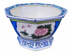 FAIANÇA, um (1) cachepot confeccionado em faiança vitrificada na tonalidade branca, formato oitavado, decorado por flores e folhagens em policromia com realces na cor azul, apresenta fios de cabelo, vide foto, base em vazados, medindo 22x35cm.