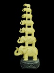 ESCULTURA ORIENTAL, uma (1) escultura representando "Sete Elefantes da Sorte" confeccionados em resina com moldagem de arabescos, apoiada sobre base na tonalidade preta, apresenta colados, medindo 42cm de altura.