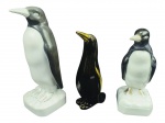 ESCULTURAS, lote com três (3) esculturas representando pinguins de modelos, tamanhos e decorações distinta, 2 confeccionados em porcelana branca e 1 em faiança, apresentam falhas na pintura, maior medindo 26cm e menor 21cm.