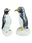 ESCULTURAS, duas (2) esculturas representando pinguins confeccionadas em porcelana na tonalidade branca com pintura na tonalidade preta, ambas com falhas na pintura, 1 com fio de cabelo na base, medindo 23cm e 21cm.