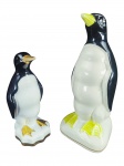 ESCULTURAS, duas (2) esculturas representando pinguins confeccionadas em porcelana na tonalidade branca com pintura na tonalidade preta, ambas com falhas na pintura, medindo 25cm e menor 18cm.