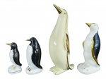 ESCULTURAS, lote com quatro (4) esculturas representando pinguins de modelos, tamanhos e decorações distinta, 2 confeccionados em porcelana branca e 2 em faiança, apresentam falhas na pintura, maior medindo 27cm e menor 12,5cm.