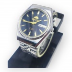 RELÓGIO, um (1) relógio de pulso masculino, da marca Orient, linha Crystal, modelo/referência A09100-71 FA, com mecanismo automático de 21 rubis, mostrador preto, marcadores e ponteiros dourados, calendário duplo com indicação de dia da semana e data, caixa e fundo em aço inoxidável, resistente à água, pulseira metálica e botão auxiliar lateral, necessita revisão, ao dar corda o ponteiro de segundos meche, porém, coroa um pouco emperrada, caixa medindo 3,5cm de diâmetro.