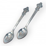 COLECIONISMO, duas (2) colher souvenir em metal prateado, da Rolex Bucherer Watches, Zürich, com cabo ornamentado em relevo trazendo brasão e inscrições da marca, e concha decorada com vista arquitetônica da cidade de Zurique, Suíça, falhas na prateção.