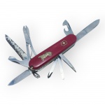 CUTELARIA, um (1) canivete suíço multifuncional, da marca Victorinox, com empunhadura em material sintético vermelho, emblema da cruz suíça e decoração representando automóvel antigo, sinais de uso e leves oxidações, vendido no estado da foto, medindo 20cm de comprimento aberto.