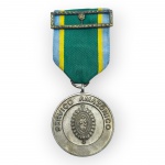 MILITARIA, uma (1) medalha alusiva ao Serviço Amazônico, confeccionada em metal prateado, com emblema em relevo e inscrição SERVIÇO AMAZÔNICO no anverso; reverso decorado com representação arquitetônica e inscrição AMAZÔNIA. Acompanha fita em tecido nas cores verde, azul e amarelo, com passador metálico ornamentado, medindo 9x4cm.