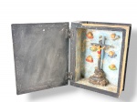 ARTE SACRA, um (1) oratório de viagem confeccionado em madeira representando bíblia, patina escurecida, entalhado por folhagens, cruz e ovelha em relevo com realces em douração, interior com fundo azul, crucifixo e figuras angelicais em policromia, medindo 18,5x14,5cm.